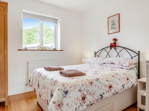a bedroom with a bed with a floral bedspread at Chestnut Lodge in Old Buckenham