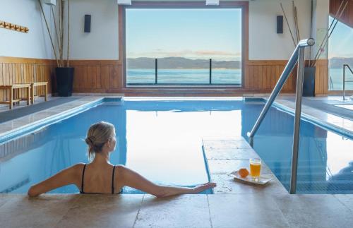a woman sitting in a swimming pool with a tray of orange juice at Los Cauquenes Resort + Spa + Experiences in Ushuaia