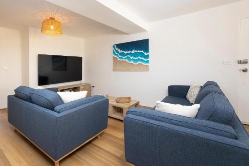 a living room with two blue couches and a tv at Sunlake 7 in Forster