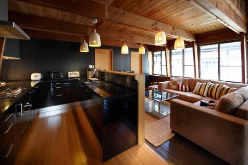 a kitchen and a living room with a couch at Hakuba Mountain Cabin in Hakuba
