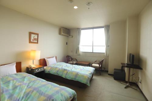 a hotel room with two beds and a television at Hotel Chalet Ryuo in Yamanouchi