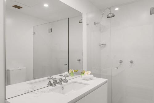 a white bathroom with a sink and a shower at The Coogee View Beachfront Serviced Apartments in Sydney