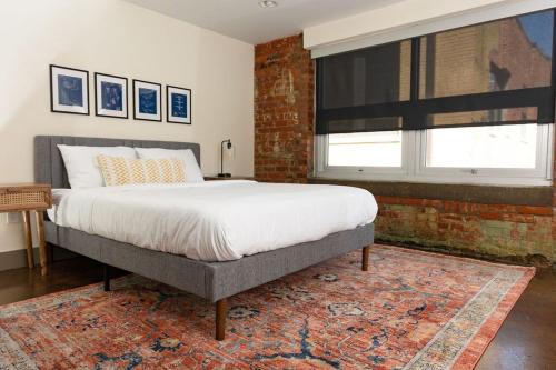 a bedroom with a bed and a brick wall at Stunning 2 Br Loft Smack In The Heart Of Downtown in Roanoke