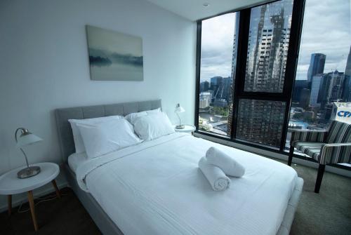 a bedroom with a white bed with a large window at Stunning 2-Bedroom Oasis in the Heart of Southbank in Melbourne