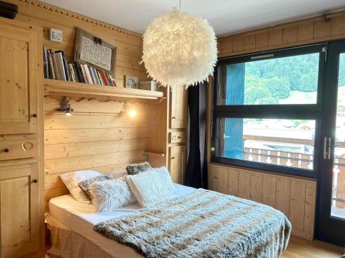 une chambre avec un lit et une grande fenêtre dans l'établissement Les Gets - Appartement rénové au pied des pistes, central, 4 pers, balcon, parking privé - FR-1-623-256, aux Gets