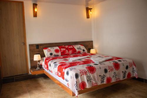 a bedroom with a bed with red and white blankets and pillows at Hostería El Sendero - Cocorná in Cocorná