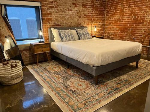 a bedroom with a bed and a brick wall at Luxury 2 Bedroom Apt With Exposed Brick Downtown in Roanoke
