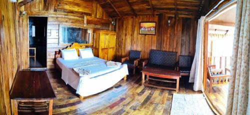 ein Schlafzimmer mit einem Bett und Stühlen in einer Hütte in der Unterkunft Sea Front Cottage Little Khola in Cola