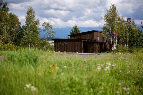 a building on the side of a road with a field at Rising Sun Furano in Kami-furano
