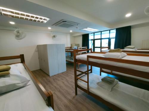 a room with three bunk beds and a desk at Agape Hostel in Sibu