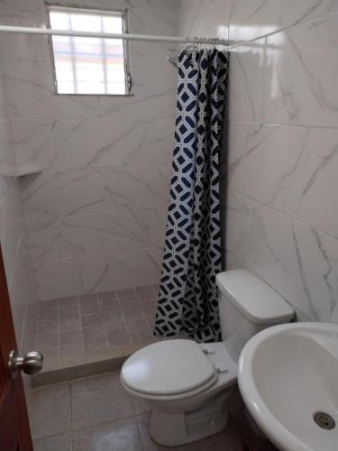 a white bathroom with a toilet and a sink at La Casa Buena Esperanza in Penonomé
