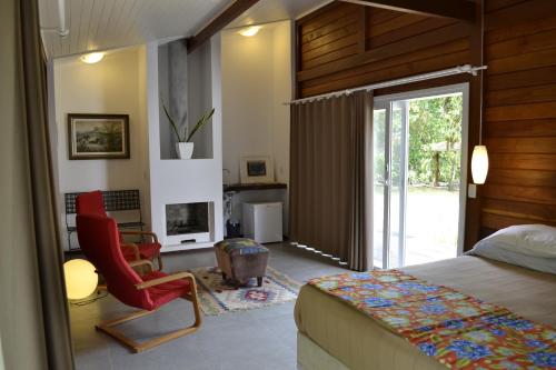 a bedroom with a bed and a chair and a fireplace at Casa da Ilha do Mel - Pousada de Charme in Ilha do Mel