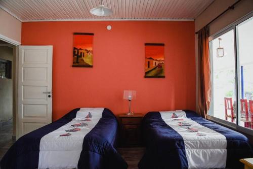 two beds in a room with an orange wall at Casa Cabra Corral in Coronel Moldes
