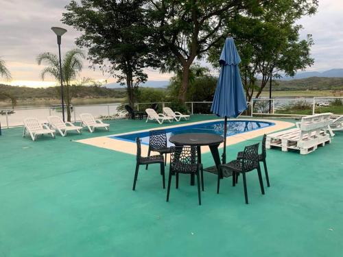 a table with chairs and an umbrella next to a pool at Casa Cabra Corral in Coronel Moldes