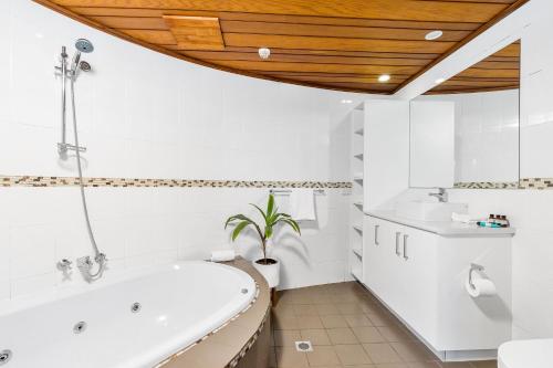 a bathroom with a tub and a toilet and a sink at Aquarius Backpackers Resort in Byron Bay