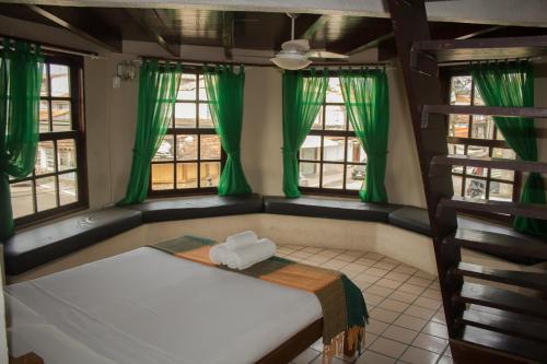 um quarto com uma cama com cortinas verdes e janelas em Pousada Casa da Pedra em Búzios