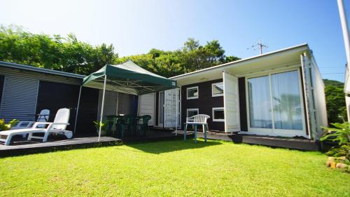 a small house with a yard with chairs and an umbrella at Panari-パナリ in Ube