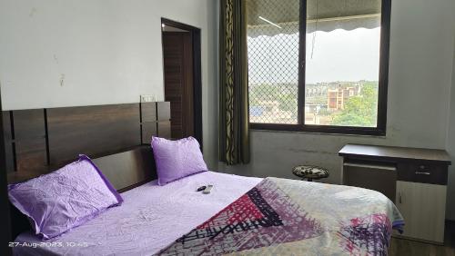 a bedroom with a bed with purple pillows and a window at Luxury room set OSHO Villa in Jaipur