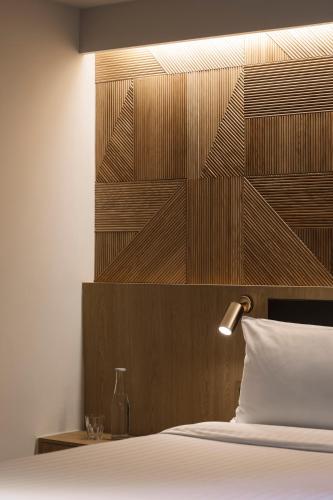 a bedroom with a bed with a wooden headboard at KēSa House, The Unlimited Collection managed by The Ascott Limited in Singapore