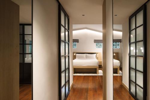 1 dormitorio con cama y espejo en KēSa House, The Unlimited Collection managed by The Ascott Limited en Singapur