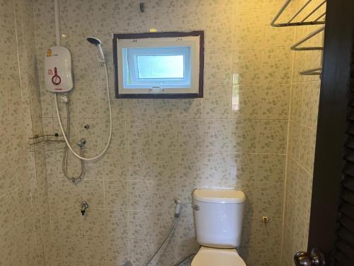 a bathroom with a shower and a toilet and a window at Chiang Mai Slowtime in Chiang Mai