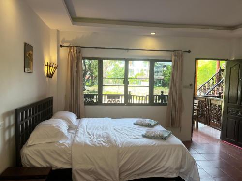 a bedroom with a large bed and a balcony at Chiang Mai Slowtime in Chiang Mai