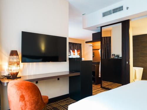 um quarto de hotel com uma televisão, uma cama e uma cadeira em Stay Collection Bukit Bintang em Kuala Lumpur