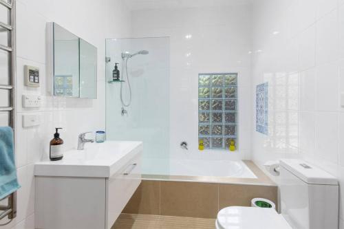 a white bathroom with a sink and a toilet at Ocean Blue Escape - Beachside Living & Granny Flat in Wollongong