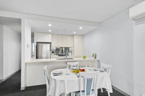 a white kitchen with a white table and chairs at City Beach Escape - Wollongong Waterside Serenity in Wollongong