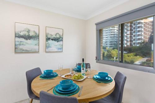 a dining room with a wooden table and chairs and a window at North Beach Escape - Balcony Sunrises and Ocean Walks in Wollongong