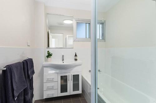 une salle de bain blanche avec un lavabo et une douche dans l'établissement North Beach Escape - Balcony Sunrises and Ocean Walks, à Wollongong