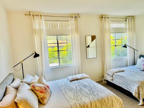 a bedroom with two beds and two windows at The Clouds in Los Angeles