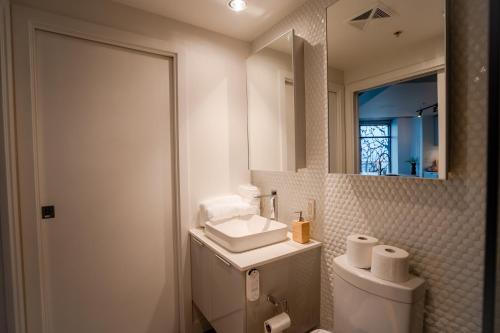 uma casa de banho com um WC, um lavatório e um espelho. em High rise Apartment em Vancouver