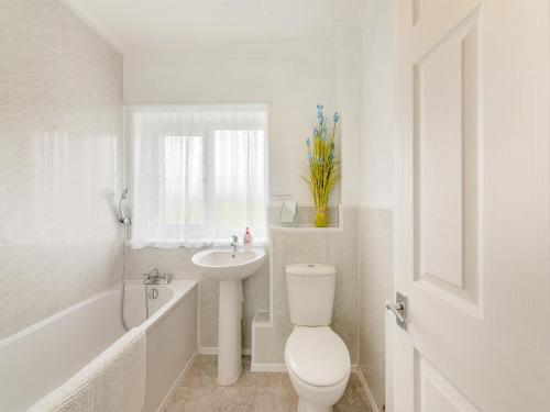 a white bathroom with a toilet and a sink at Westfield in Newbiggin-by-the-Sea