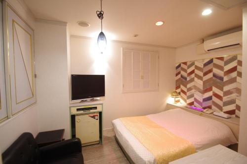 a bedroom with a bed and a flat screen tv at Hotel PRINCESS2 大人専用 in Tokyo