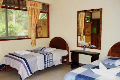 a bedroom with two beds and a mirror at Paraiso Pilcopata Inn in Pillcopata