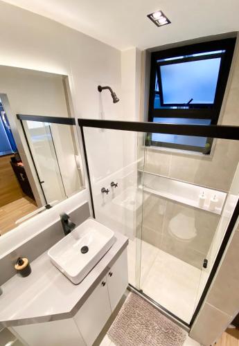a white bathroom with a sink and a shower at Loft lindo e aconchegante no centro de Teresópolis in Teresópolis