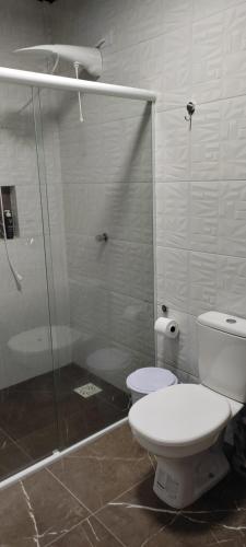 ein Bad mit einem WC und einer Glasdusche in der Unterkunft Chácara Monte Cristo in Aguas Mornas