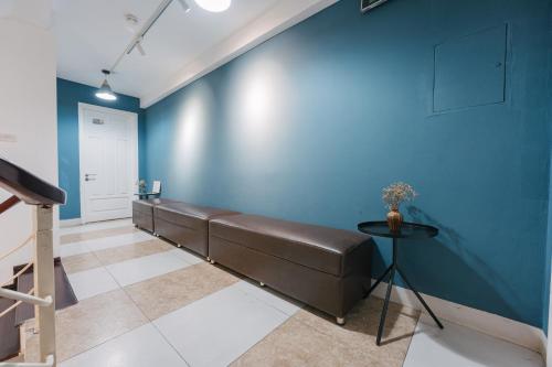 a waiting room with a brown leather bench against a blue wall at Cheers Hostel Hanoi in Hanoi