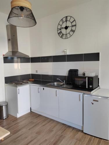 une cuisine avec des placards blancs et une horloge murale dans l'établissement Bel appartement, à Nîmes