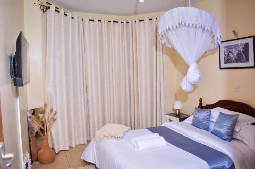 a bedroom with a bed and a window with curtains at Madiniplace 1 - Flexible 1-3BR Apartment near JKIA & SGR in Nairobi