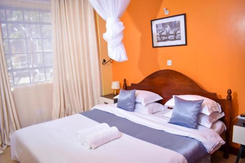 una camera con 2 letti e una parete arancione di Cosy House near Airport JKIA Train SGR a Nairobi