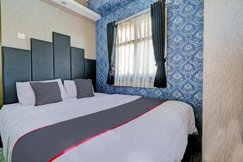 a bedroom with a large bed with blue walls at Collection O 93070 Apartemen The Suite Metro By Sultan Property Ii in Bandung