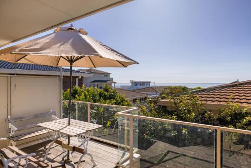 a patio with a table and an umbrella on a balcony at Magnificent sunrises, Oceanbeach & Sea Views in Tauranga
