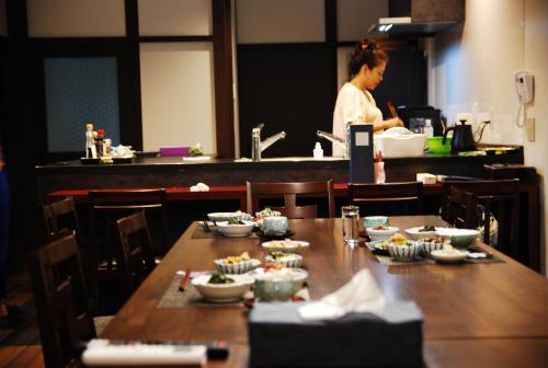 una donna in una cucina con un tavolo con sopra del cibo di 金沢一棟宿 海泉 Restoring In Kanazawa KAISEN a Kanazawa