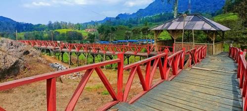 een rode brug met een houten loopbrug en een hut bij Gunung bangku ciwidey rancabali camp in Ciwidey