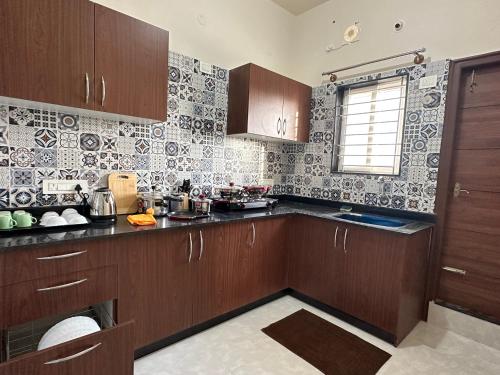 a kitchen with wooden cabinets and tiles on the wall at SanTrupthi A Stay at Home in Chikmagalūr
