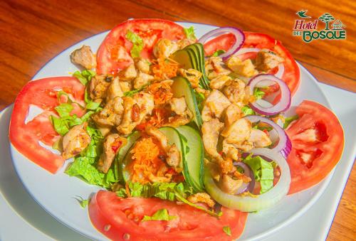a plate of food with a salad and tomatoes at Hotel del Bosque in Río Cuarto