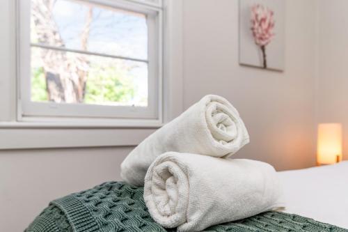 a pile of towels sitting on top of a bed at Golden Square Gold Class Guest House, Bendigo in Golden Square