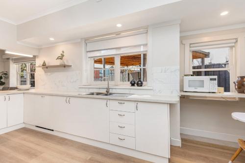 a kitchen with white cabinets and a microwave at Golden Square Gold Class Guest House, Bendigo in Golden Square